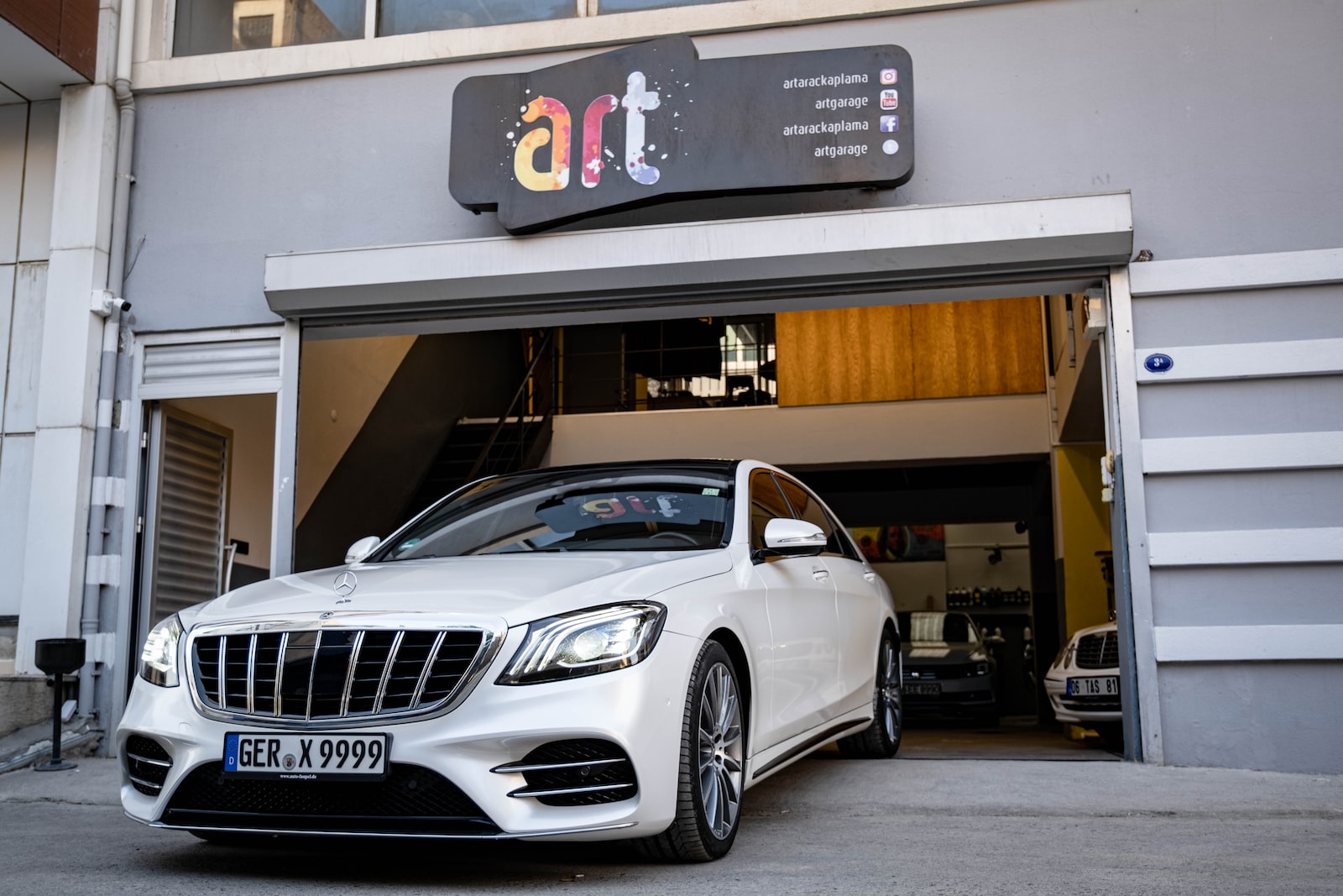 Photographie d'une Mercedes devant un garage automobile